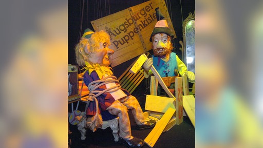Die Puppen Räuber Hotzenplotz und der Kasperl sind im Augsburger Puppentheatermuseum "Die Kiste" in einer Vitrine ausgestellt