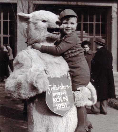 Ein als Eisbär verkleideter Mensch hat einen Jungen auf dem Arm.