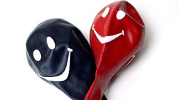Schwarzer und roter Luftballon mit Smiley - Symbol für eine GroKo aus Union und SPD