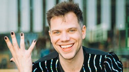 Dramaturg und Kulturwissenschaftler Lasse Scheiba zeigt seine Hand mit lackierten Fingernägeln.