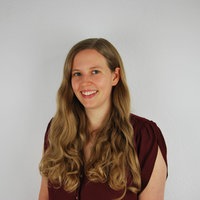 Mirjam Ratmann steht vor einer weißen Wand und schaut in die Kamera