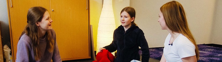 In der Trauergruppe sitzen drei Mädchen um ein Tablett mit Kerzen herum
