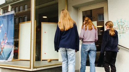 Drei Mädchen mit rotblonden Haaren stehen vor einem Hauseingang. 