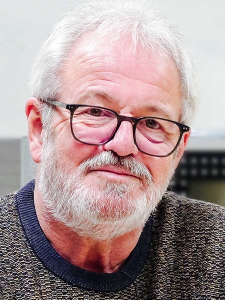 Günter Döker sitzt leicht lächelnd in einem Klassenzimmer