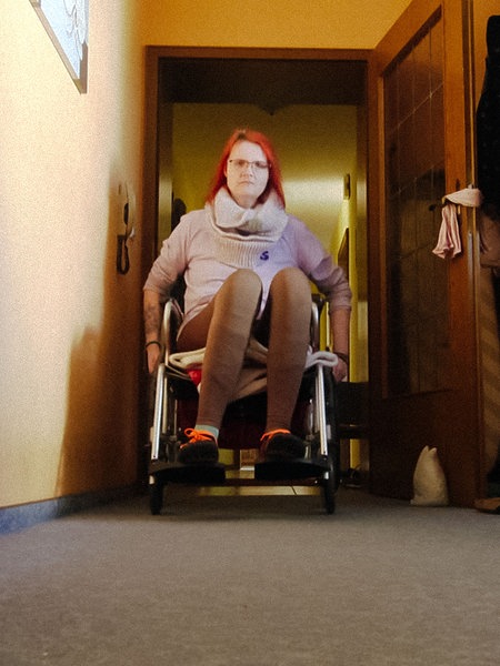 Annika Witteler sitzt im Rollstuhl in ihrem Wohnzimmer. 