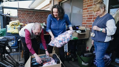 Drei Personen stehen auf einer Terasse und packen Spenden zusammen. Olivia Brandt ist eine von ihnen.