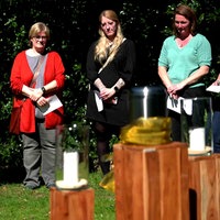 Einige Menschen stehen auf einem Friedhof um eine Urne und gedenken eines Toten