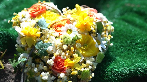 Ein Blumenkranz in Form eines Herzens liegt auf einer Wiese
