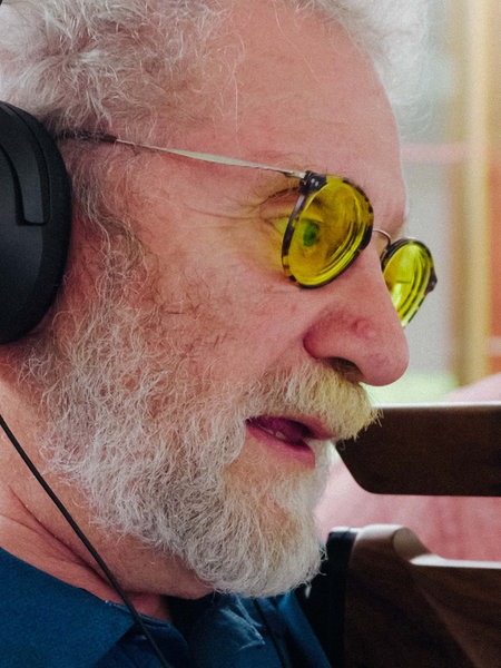 Jürgen Klamann beim Schießen. Er trägt eine Brille mit gelben Gläsern. Neben ihm steht sein Trainer, beide haben Kopfhörer auf.