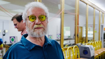 Jürgen Klamann im Interview. Er hat weiße Haare und einen weißen Bart, außerdem trägt er eine Brille mit gelb getönten Gläsern.