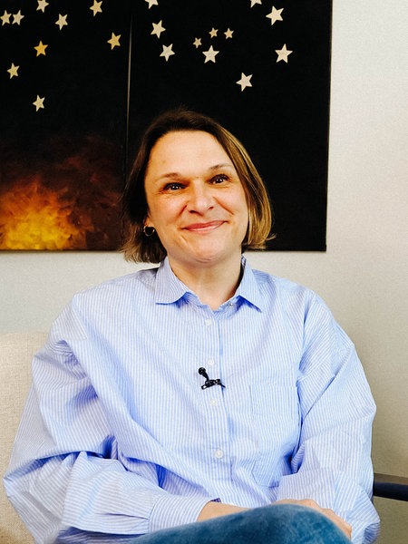 Susanne Starkmuth, eine Frau mit einer blau-weiß gestreiften Bluse, sitzt in einem Büro.