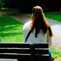 Sandra Riesener, eine Frau mit braunen langen Haaren, sitzt auf einer Bank