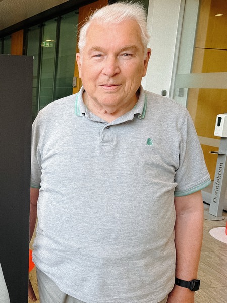 Ernst Sprick steht neben einem Schwarz-Weiß-Porträt von ihm, auf dem seine Brustkrebs-Narbe zu sehen ist