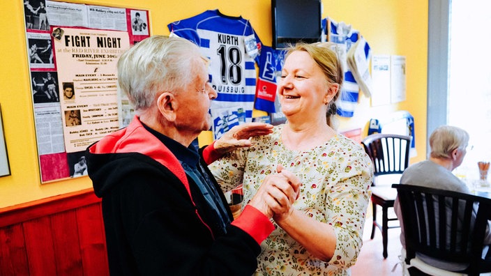Senior tanzt mit einer Frau in einer Kneipe.