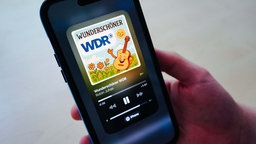 Ein Handy mit einem Lied, das abgespielt wird. Auf dem Cover steht "Wunderschöner WDR" und eine Gitarre mit Gesicht und eine Sonne mit Gesicht sind ebenfalls auf dem Cover.