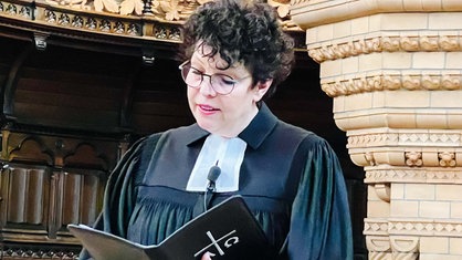 Christine Blaß steht in schwarzem Gewand mit weißer Halsbinde in der evangelischen Friedhofskirche in Wuppertal-Elberfeld und liest ihre Predigt