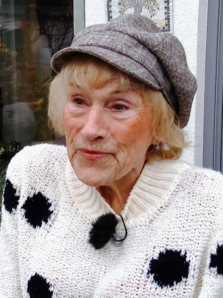 Edith Clemes trägt einen Wollpullover und eine Mütze. Sie steht auf ihrer Terrasse.