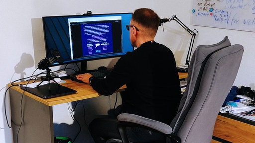 Peter Klim sitzt an einem Schreibtisch und spielt am Computer.