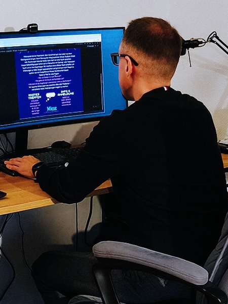 Peter Klim sitzt an einem Schreibtisch und spielt am Computer.
