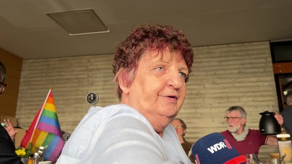 Vera Fraczewski, eine ältere Frau mit kurzen, roten Haaren, spricht in ein WDR-Mikrofon.