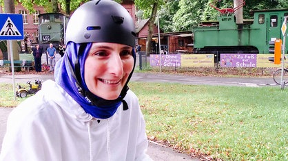 Eine Frau mit Helm sitzt auf einem Fahrradsattel.