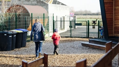 Eine Frau und ein Kind gehen über den Spielplatz der Kita