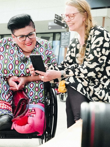 Zwei Frauen schauen gemeinsam Fotos auf einem Handy an. 