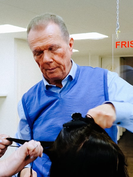 Eine Kursteilnehmerin und Hermann Wiezorek üben Haarschneidetechniken an einem Modell. 