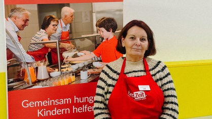 Eine Frau mit mittellangen braunen Haaren und einer roten Schürze.
