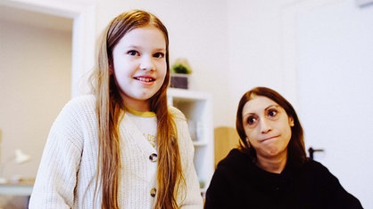 Die neunjährige Ida steht links im Vordergrund und lächelt verlegen in die Kamera. Hinter ihr sitzt Nanis Taha