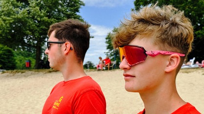 Henning Thielemeyer steht neben einem DLRG-Kollegen. Beide haben eine Sonnenbrille auf.