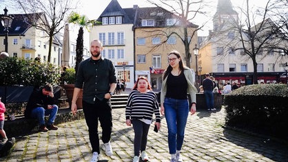 Riana Yiannakis und ihre beiden Hospizhelfer laufen über einen belebten Platz in der Stadt