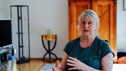 Riana Yiannakis Mutter Vera sitzt in einem Innenraum auf einem Stuhl