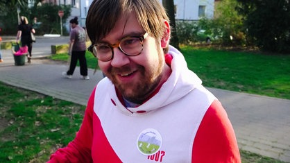 Ein junger Mann mit Brille schaut direkt in die Kamera.