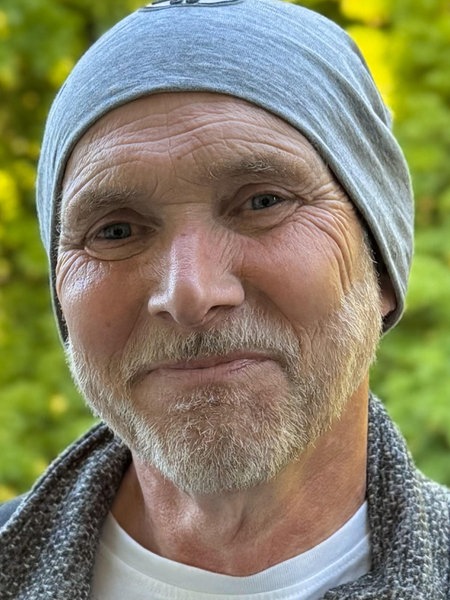 Henrik Strübli hat eine Mütze auf dem Kopf und lächelt in die Kamera