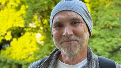 Henrik Strübli hat eine Mütze auf dem Kopf und lächelt in die Kamera