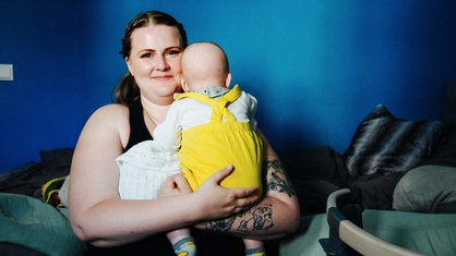 Eine Frau sitzt auf einer Couch und hält ihr Baby auf ihrem Schoß.