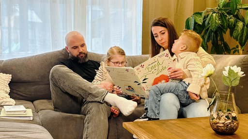 Lian, seine Schwester und seine Eltern Jenny Kloss und Oliver Mächler auf einem Sofa.