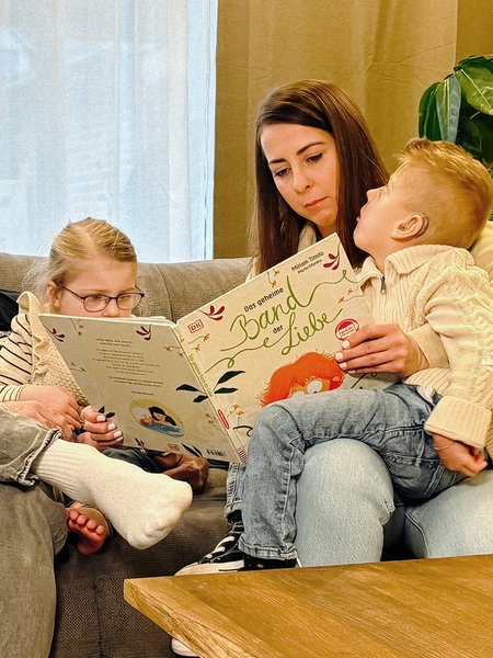 Lian, seine Schwester und seine Eltern Jenny Kloss und Oliver Mächler auf einem Sofa.