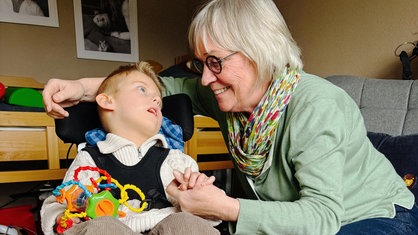Ilse Worms-Graaf im Kinderzimmer von Lian. Lian hält buntes Spielzeug in der Hand. Die andere Hand hält Ilse fest.
