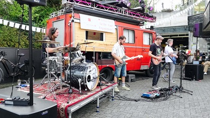 Eine Band steht vor einem alten Feuerwehrwagen und spielt ein Konzert.