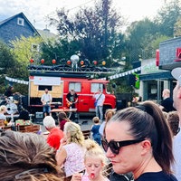 Eine vierköpfige Band steht vor einem alten Feuerwehrauto und spielt ein Konzert.