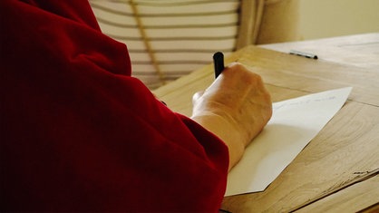 Ein Closeup einer Hand, die einen Brief schreibt.