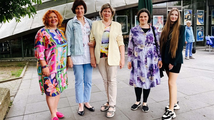 Fünf Frauen unterschiedlichen Alters stehen vor einem Gebäude. 