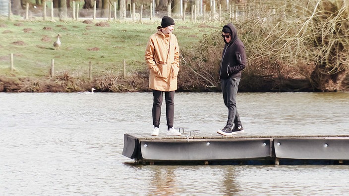Carleen Thierbach und ihr Partner laufen über einen Steg am See.