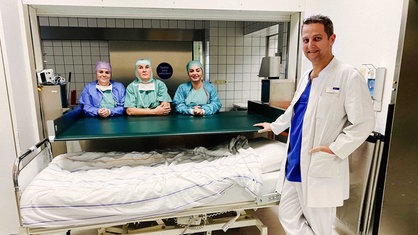 Norbert Nosal lehnt vorne am OP-Tisch. Drei OP-Helferinnen lehnen sich im Hintergrund ebenfalls auf den Tisch.