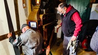 Zwei Männer in Arbeitskleidung reparieren eine alte Mühle