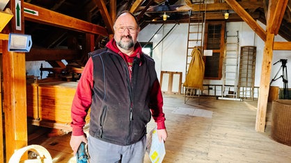 Ein Mann in Arbeitskleidung steht in einer alten Mühle