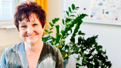 Eine Frau mit kurzen braunen Haaren lächelt in die Kamera