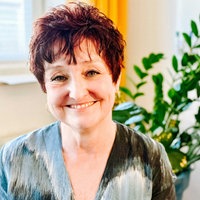 Eine Frau mit kurzen braunen Haaren lächelt in die Kamera